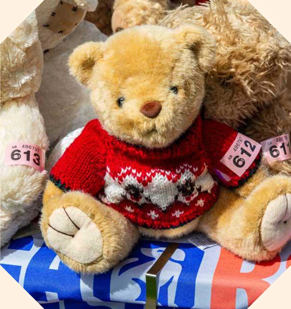 A teddy bear with a red jumper and a raffle ticket.