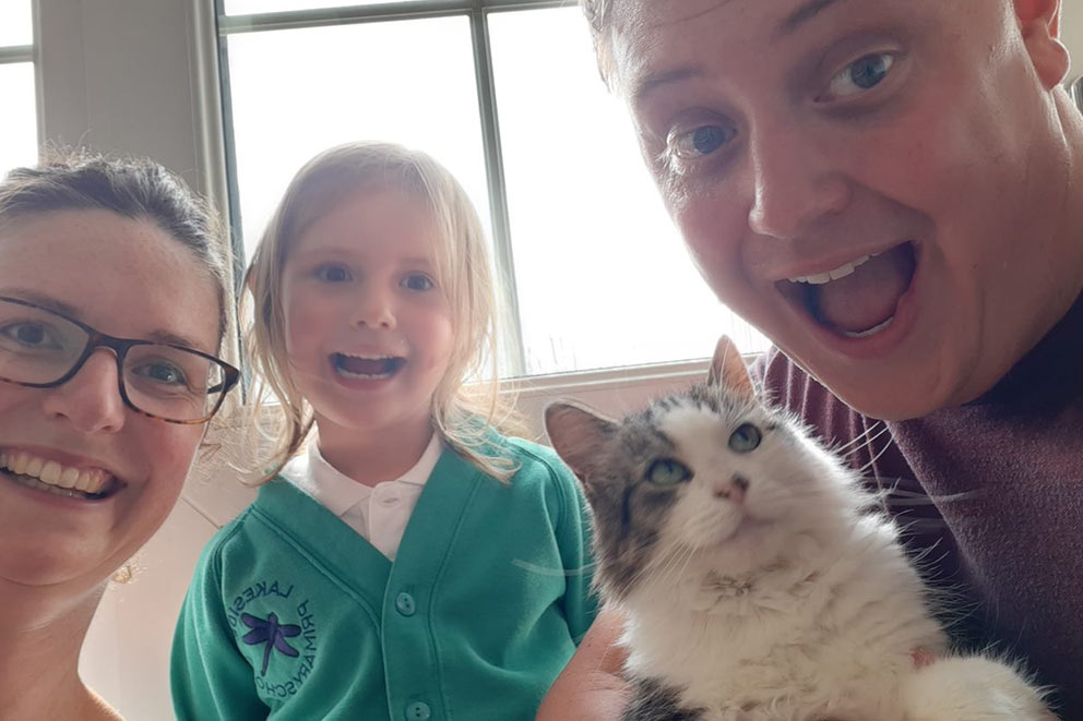 Chris O’Brien and his daughter take an indoor selfie with their fluffy white and tabby cat.