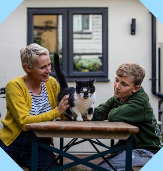 A mother and son sitting outdoors their cat, within an octopunct shape.