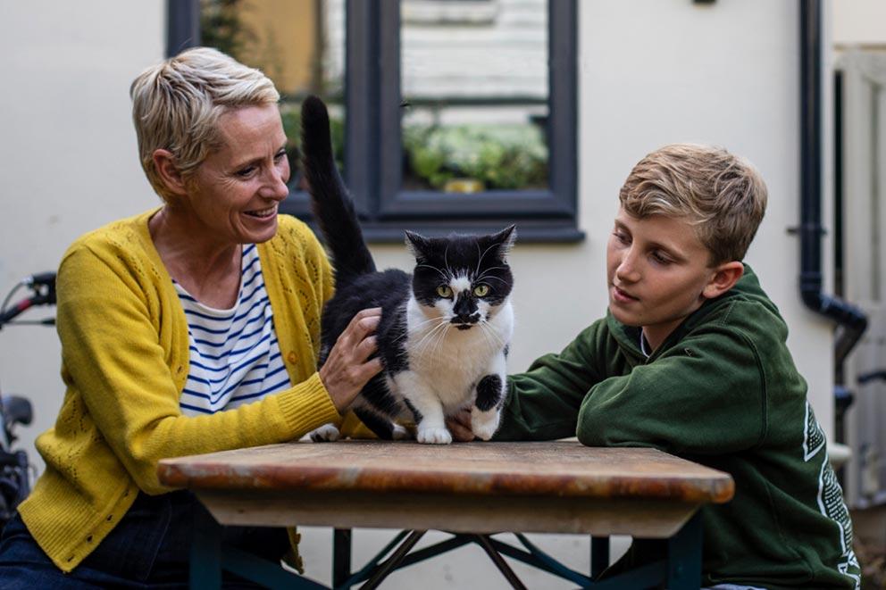 A mother and son spending time with their cat outside.