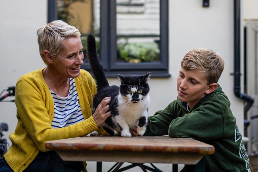 A mother and son outdoors with their cat.