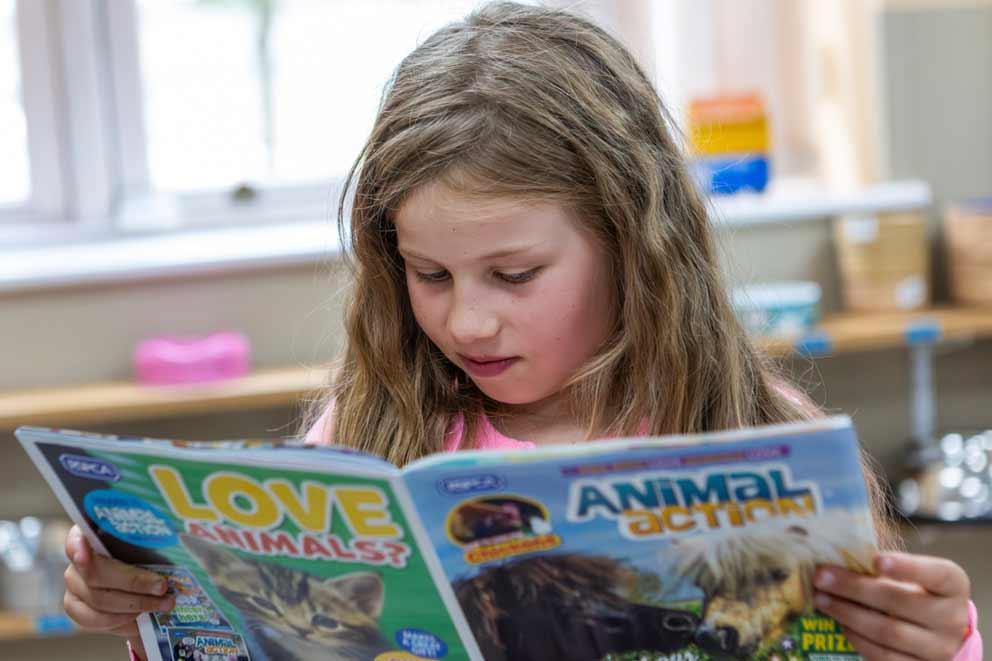 A girl reading the RSPCA's Animal action magazine.