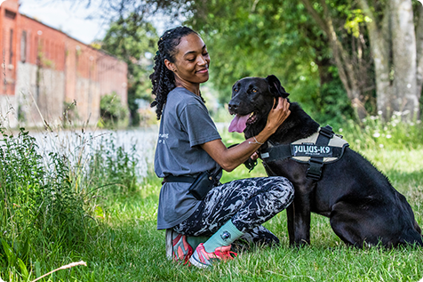 Animal Care Assistant walking a dog  in a shady spot alongside the canal