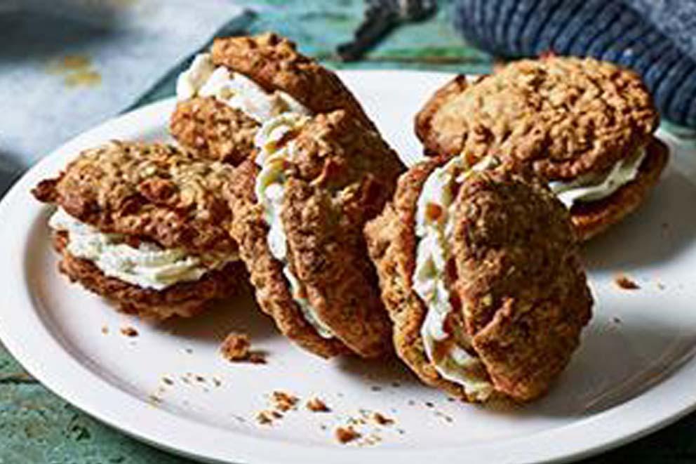 Five caramel and apple cookie sandwich biscuits on a plate.