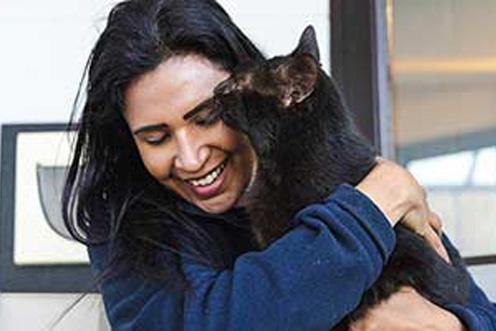RSPCA worker holds black cat, she is smiling