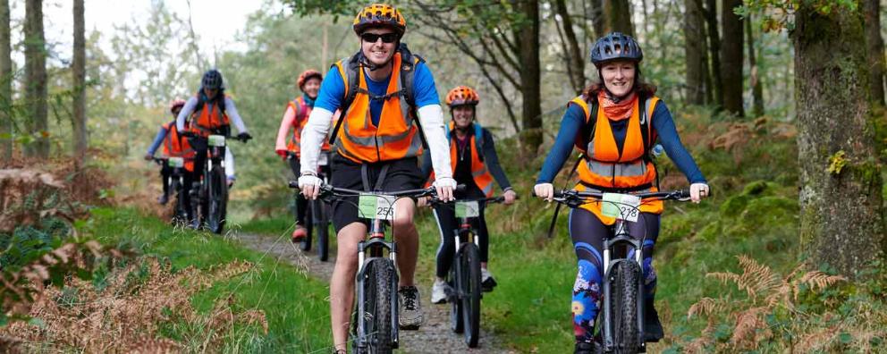 A group of cyclists cycling  in the Lake District National Park while undertaking the Lake District Triple Challenge.