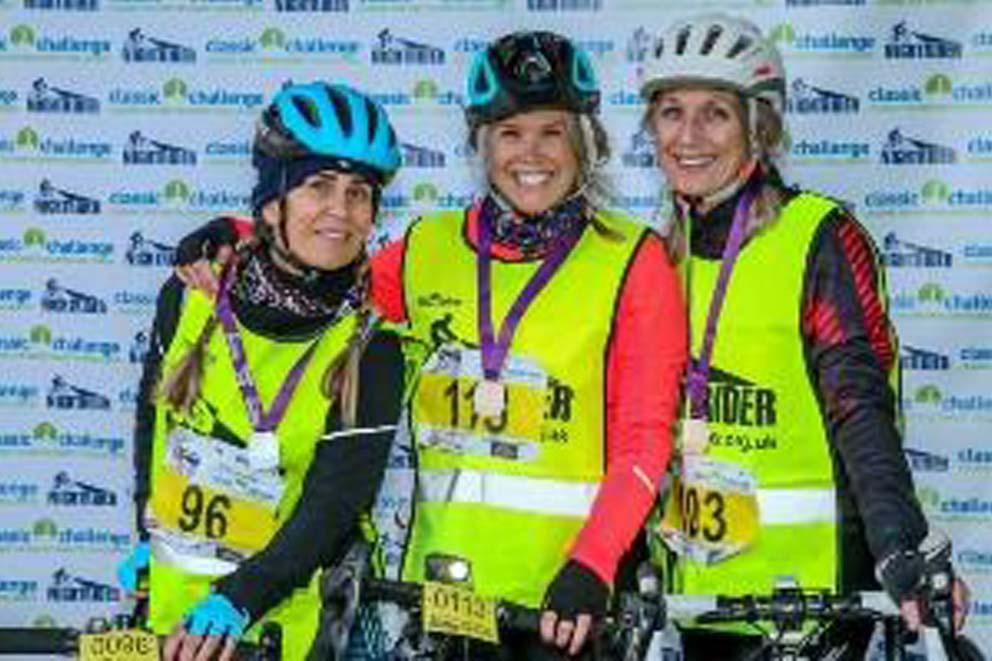 Three cylists standing with medals and bikes.